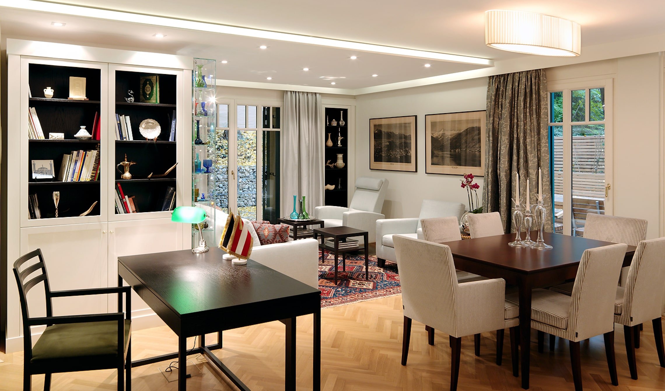Stylish living and dining area with custom-made furnishings by Neue Wiener Werkstätte, combined with a traditional carpet and curtains in natural tones. Planning & implementation by Elke Altenberger Interior Design.