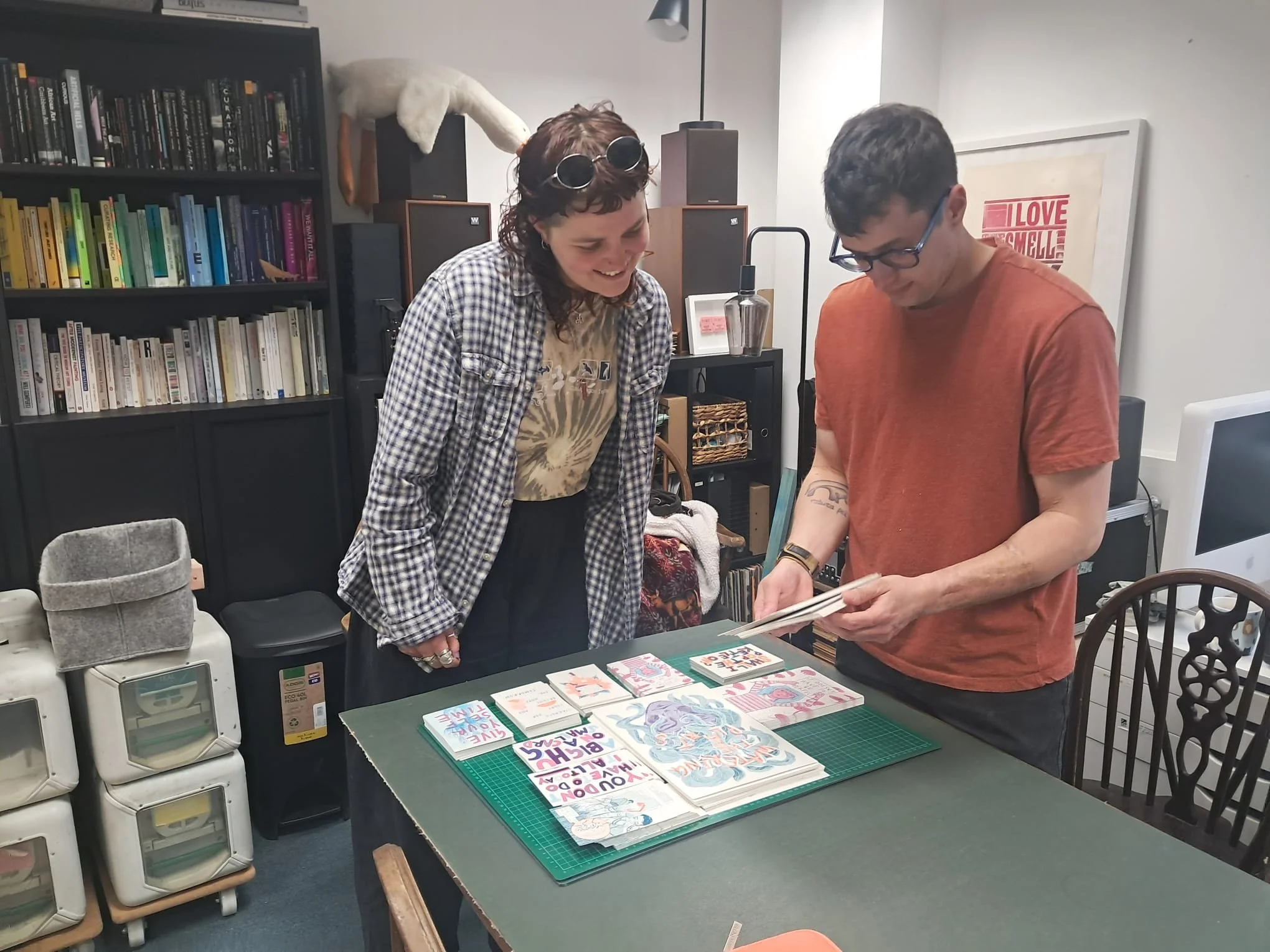 A Risograph printing studio, with print drying rack and bookshelves in the background.