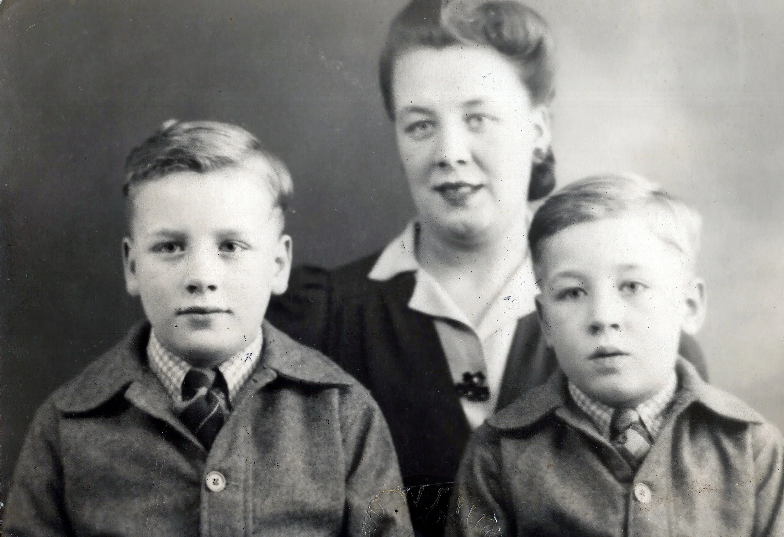 Black and white portrait of a woman with two young boys, all wearing formal clothing, from the mid-20th century.