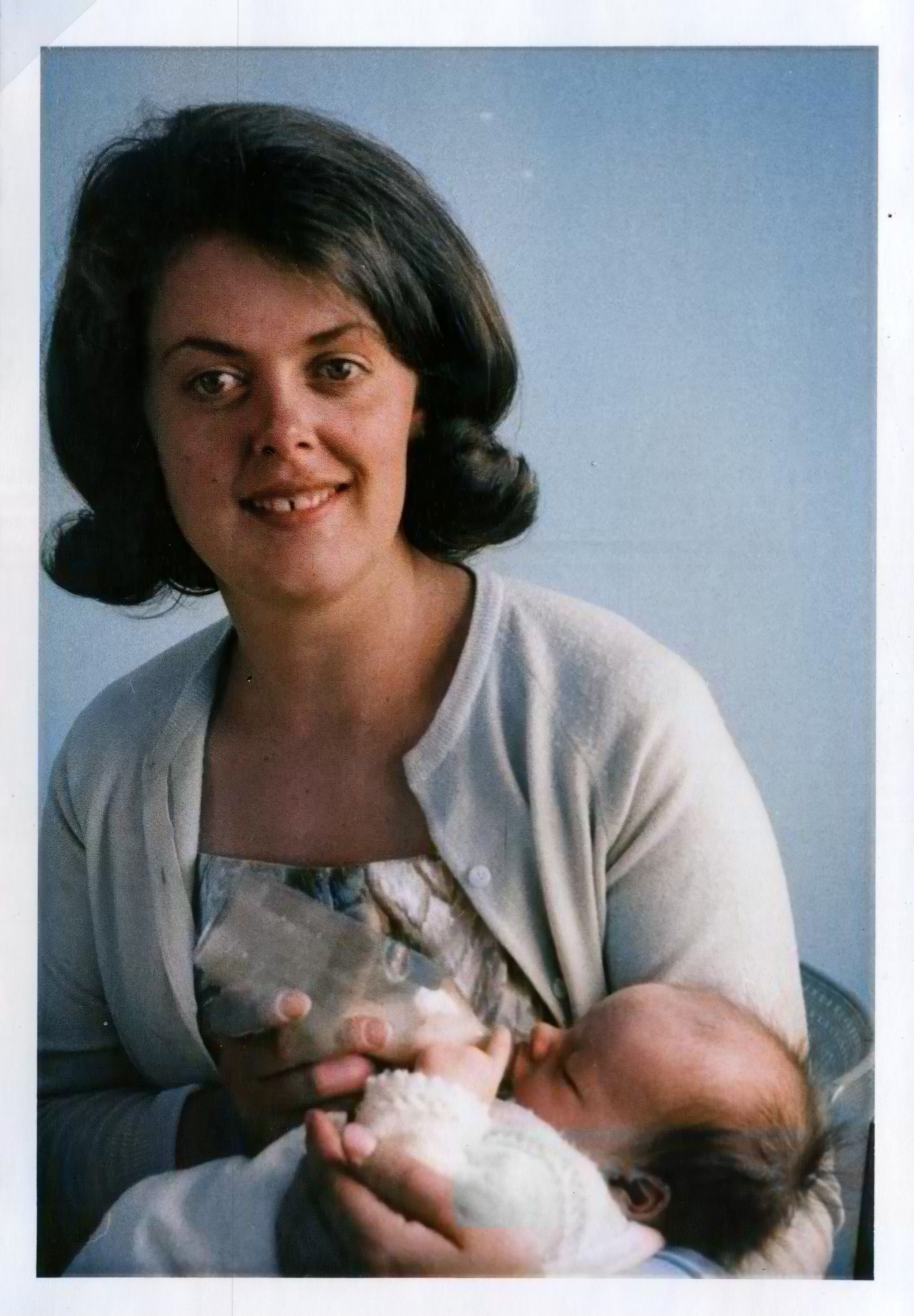 Woman smiling while holding and bottle-feeding a baby.