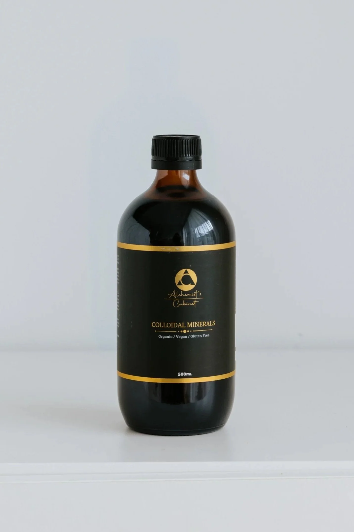 A bottle of colloidal minerals with black and gold label, on a white surface.