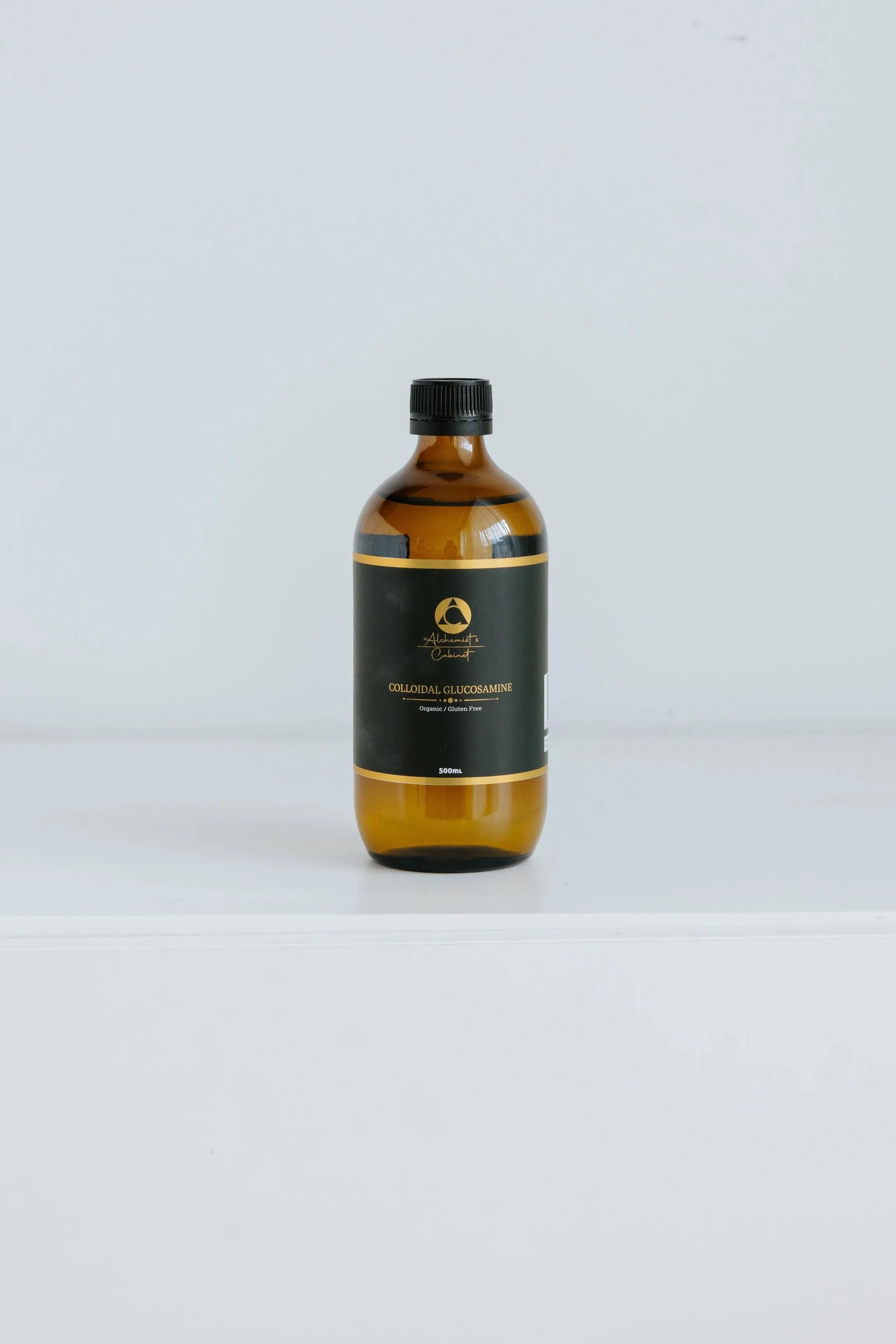A brown glass bottle labeled 'Colloidal Glucosamine' on a white surface with a plain white background.