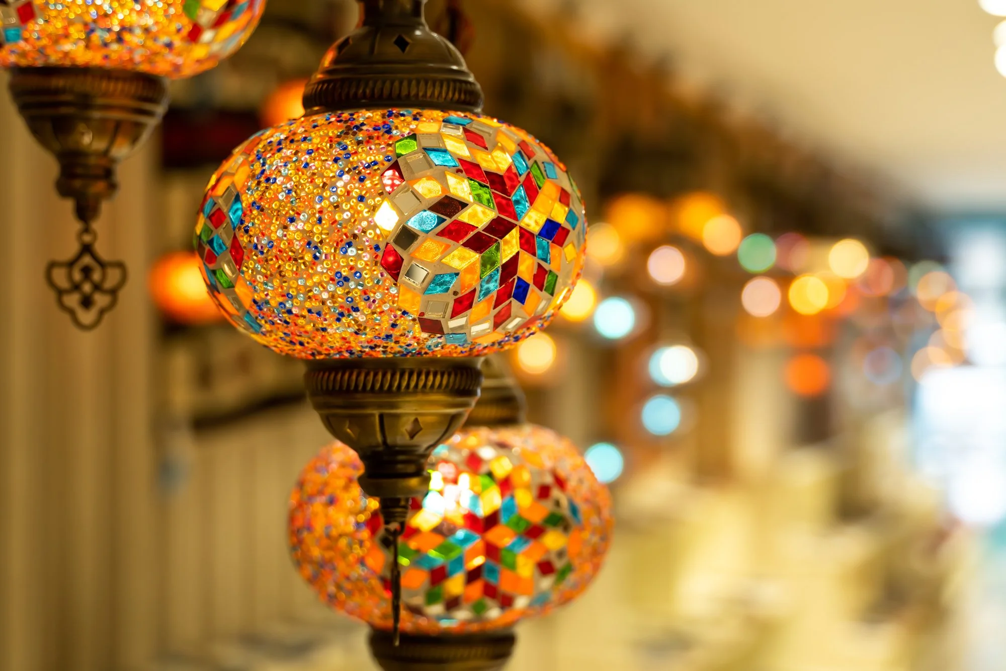 Turkish mosaic lamps hanging from a ceiling with a diffuse background.