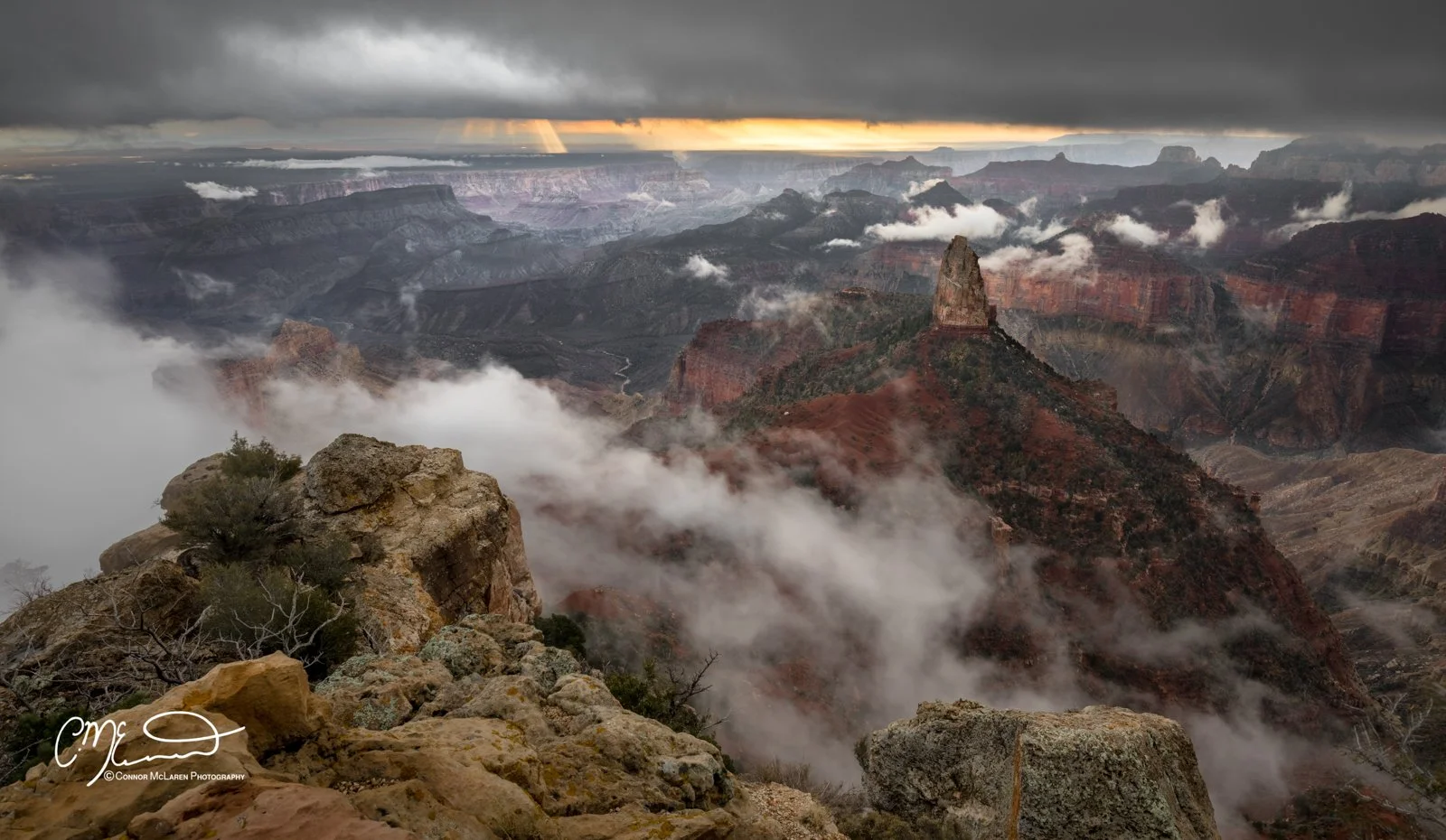 Grand Canyon, north rim, Arizona AZ, united states of america, usa. A view of the Grand Canyon with layered rock formations, clouds, and sunlight peeking through dark weather.
