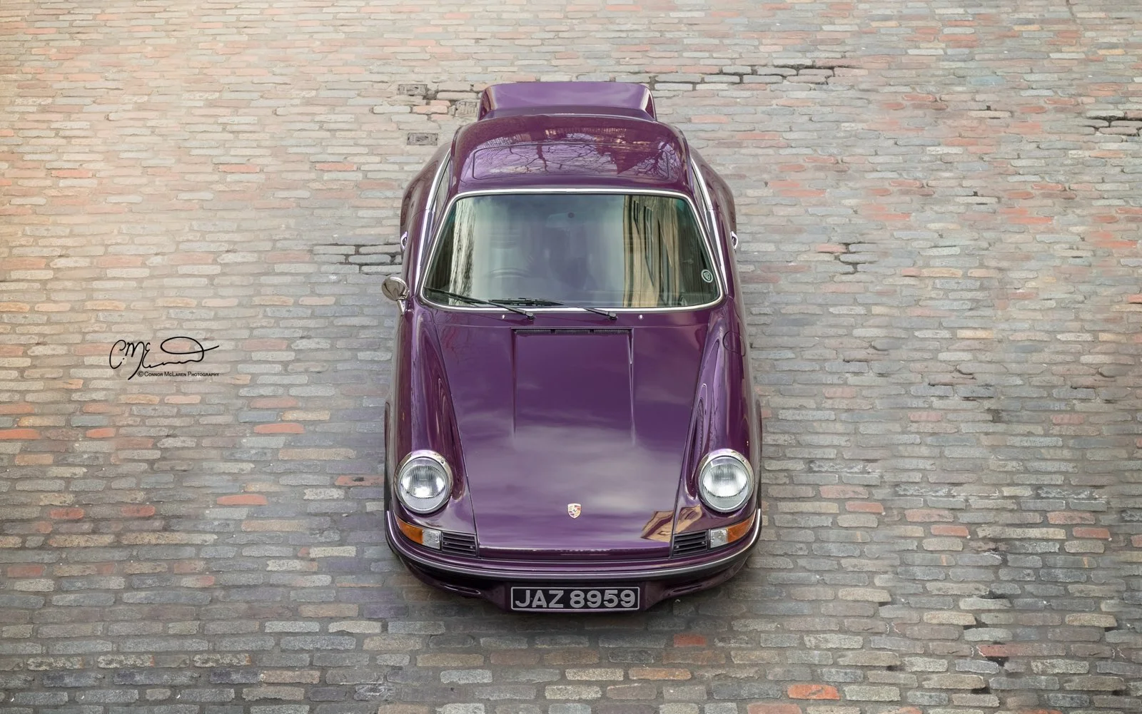 Porsche 911, 2.7RS. Top view of a vintage purple Porsche 911 parked on cobblestone street.