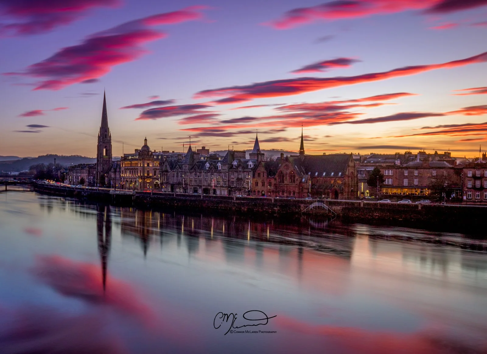 Perth Scotland, Scottish central highlands. Sunset view of a river with reflections of historic buildings and church steeples along the shoreline.