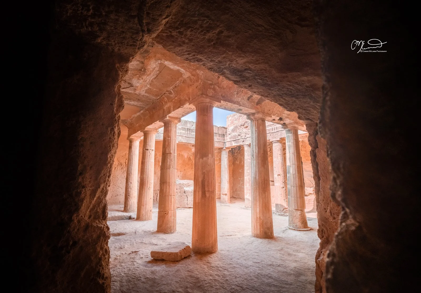 Tomb of the Kings, Cyprus. Ancient archaeological site with stone columns and walls, viewed from within a dark entrance or cave.