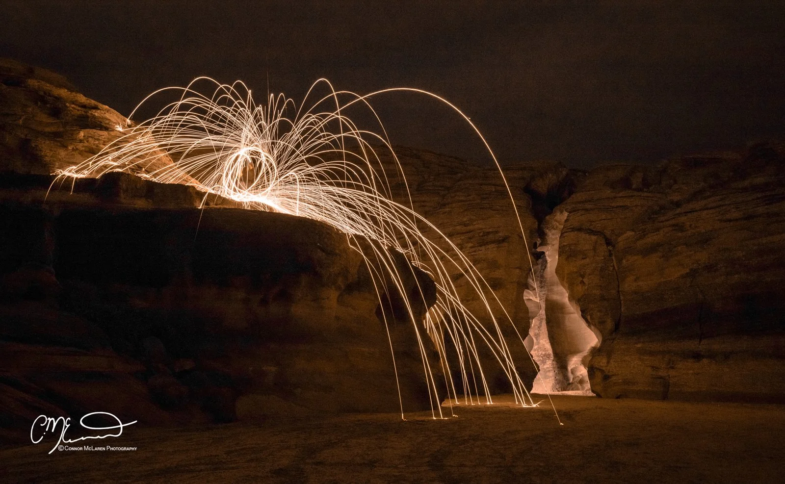 Antelope Canyon, Arizona, United States of America, USA. Steel wool spinning in a desert canyon at night with sparks flying across the dark sky.