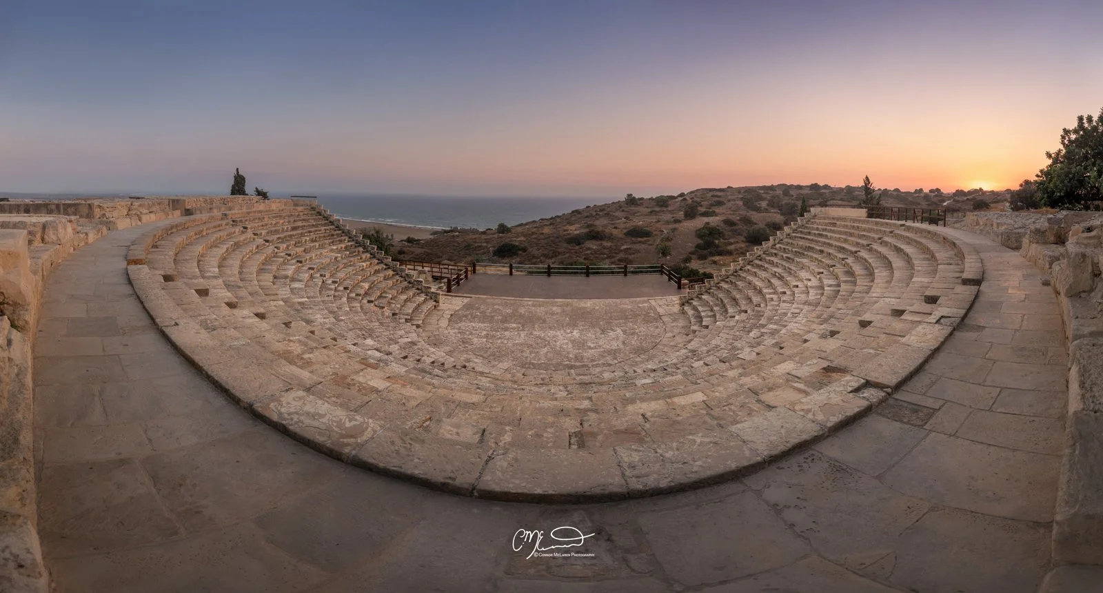 kourion, Cyprus. Ancient stone amphitheater with terraces overlooking a landscape at sunset.