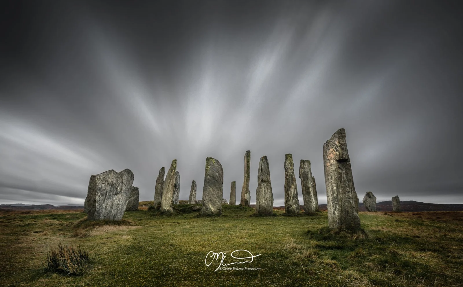 Scotland, Lewis Harris & Outer Hebrides, Callanish Standing Stones. A group of ancient standing stones arranged in a circle on a grassy plain under a cloudy, motion-blurred sky.