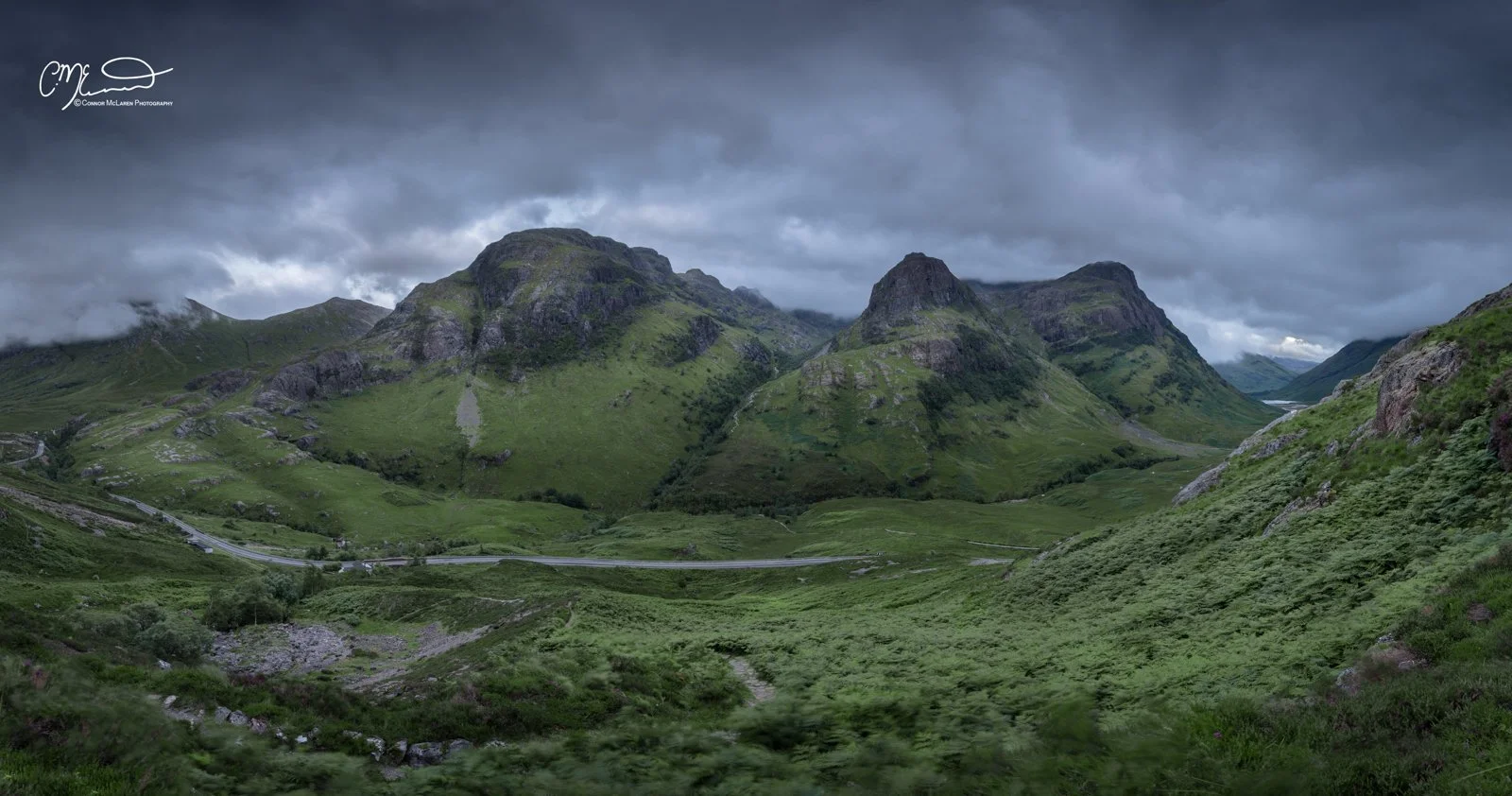 Glen Coe and Glen Etive, Western Highlands, Scotland. Green mountainous landscape with a cloudy sky, winding roads, and lush vegetation.