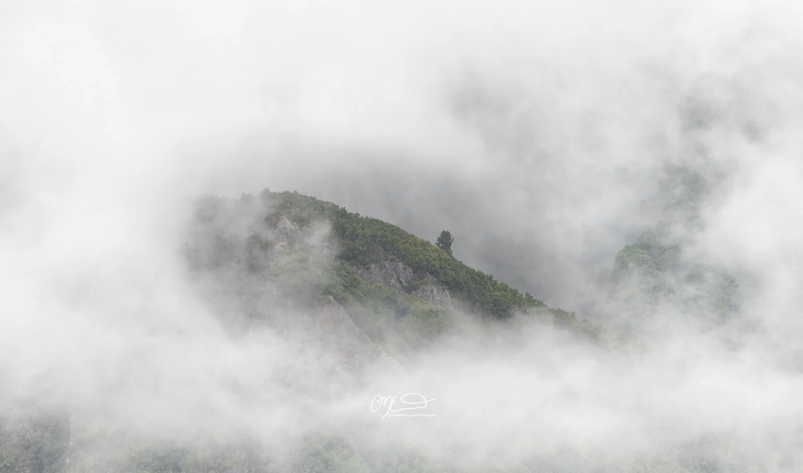 mountain top, Madeira Portugal. Mountain landscape with green hills partially covered by fog and clouds.