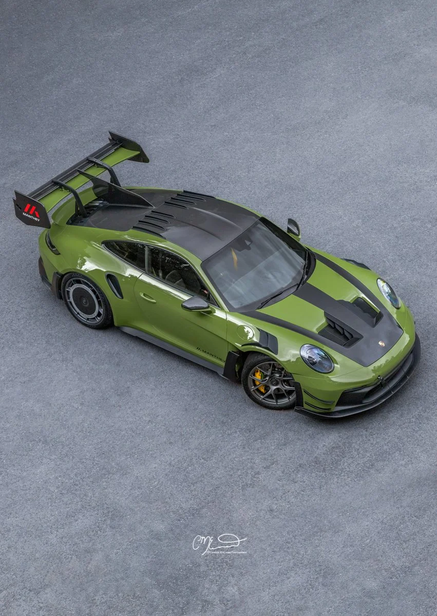 Porsche 911 GT3 RS in Paint to sample Olive green with full Manthey Racing kit. Green Porsche sports car with black racing stripe on top and a large rear wing, parked on a gray asphalt surface.
