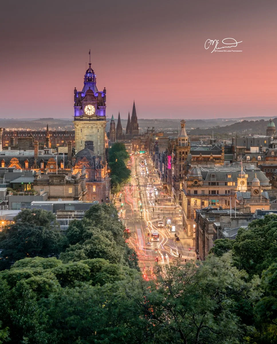 Scottish Lowlands, Scotland, Edinburgh. Cityscape of a historic city at sunset with a clock tower in the foreground and busy street lights below.