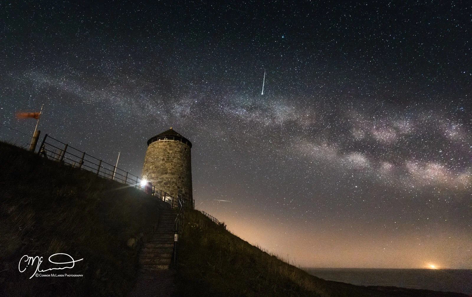st monans, fife, Night Sky, Scotland.  Nighttime landscape with a stone lighthouse on a cliff, under a star-filled sky with the Milky Way galaxy visible and shooting stars or meteors.