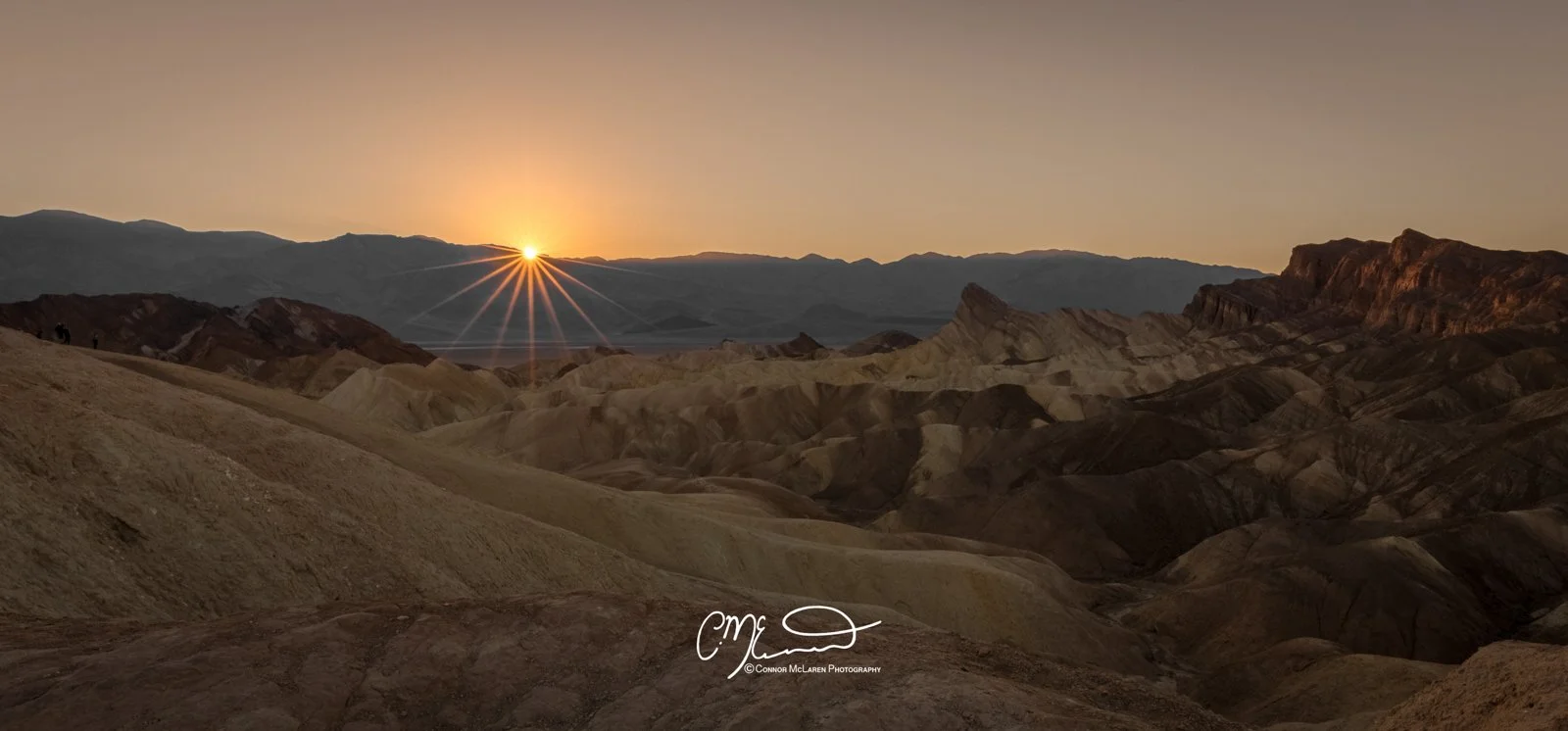 Death Valley National Park, California, United States of America, USA. Sun setting over a desert landscape with layered hills and mountains in the background.