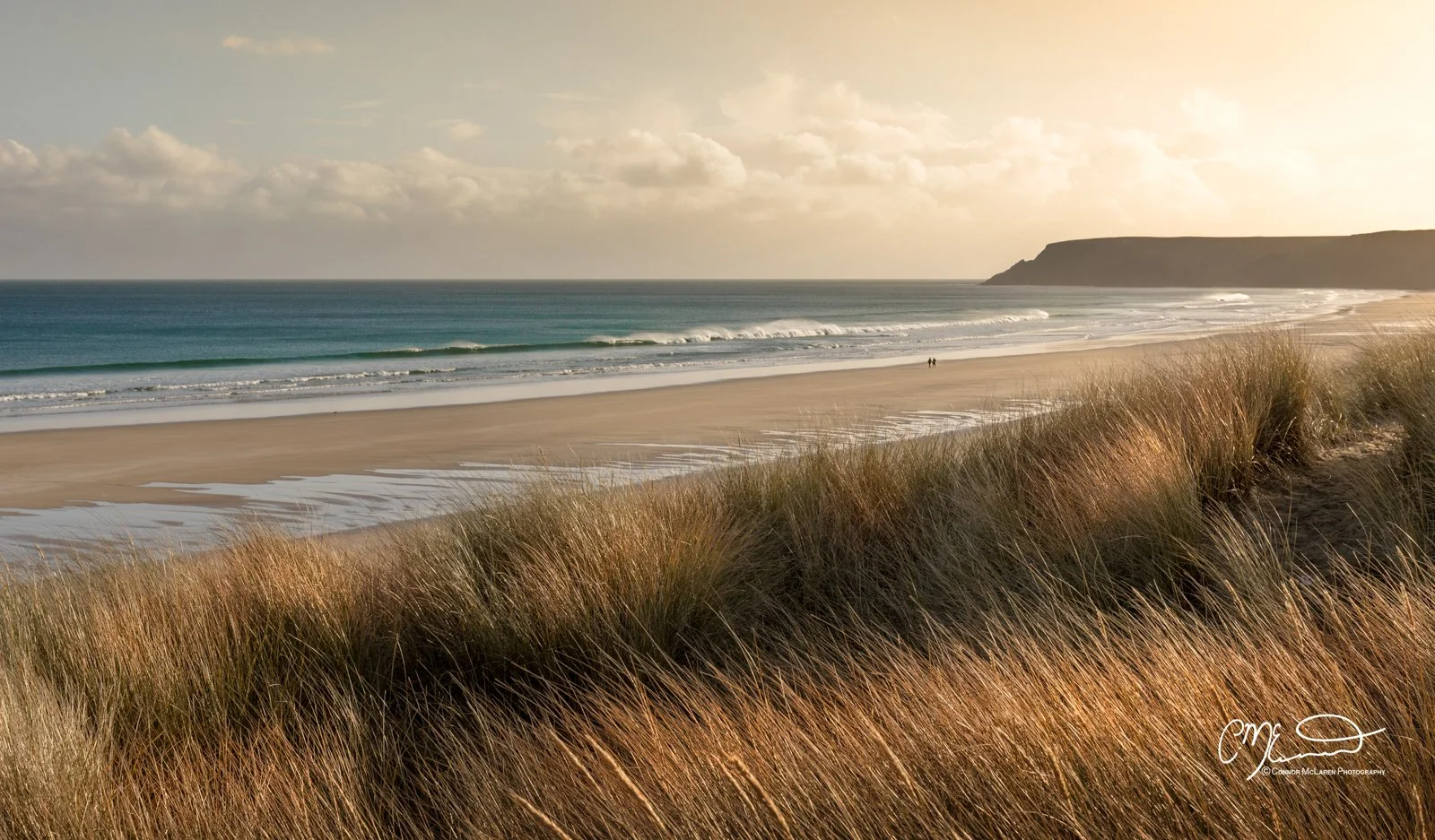 Scotland, Lewis Harris & Outer Hebrides, Tolsta. Dune grass overlooking a beach with waves and a headland in the distance at sunset.