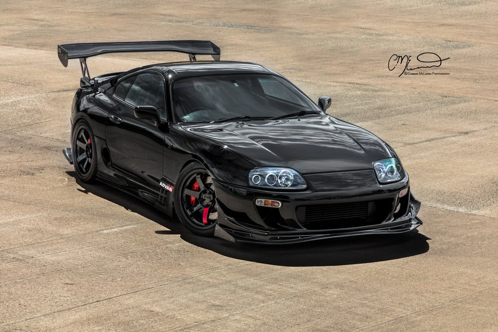 Custom Modified Toyota Supra 2JZ. A black sports car with a large rear spoiler parked on a concrete surface.