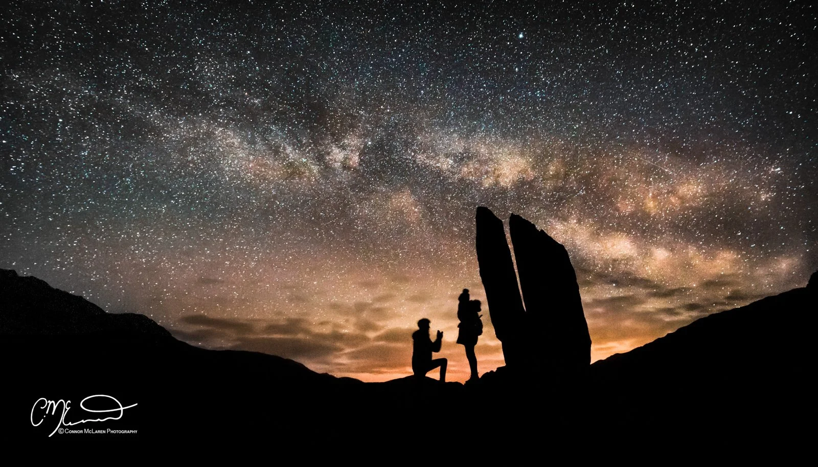 Glen Lyon Proposal under the stars, connor mclaren. Perthshire, Night Sky, Scotland.  Silhouettes of two people under a starry night sky with the Milky Way galaxy visible, mountain range in the foreground.