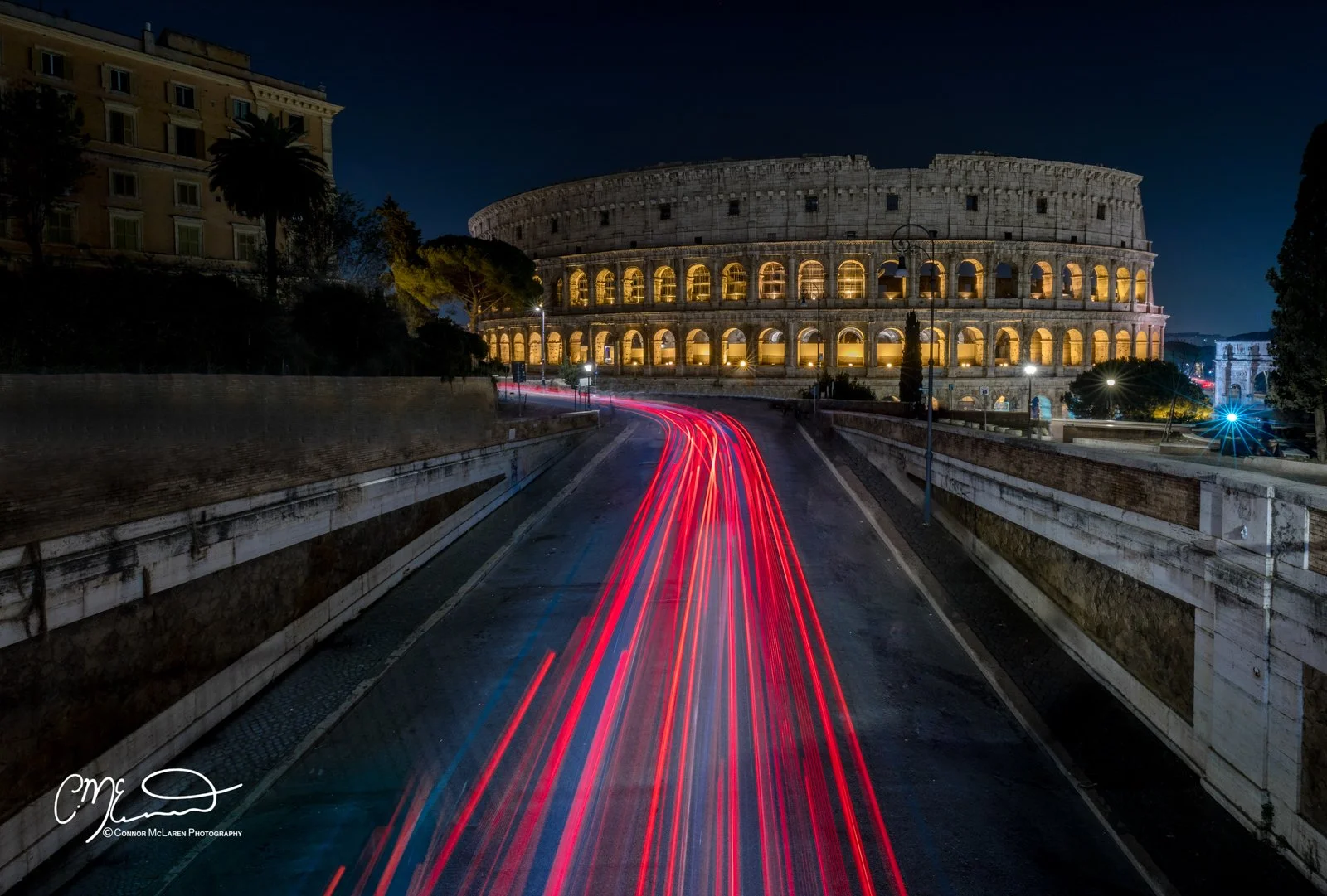 Roman Forum and colosseum, Rome & the vatican. Night view of the Colosseum in Rome, Italy, with light trails from moving vehicles on a curved road in the foreground.