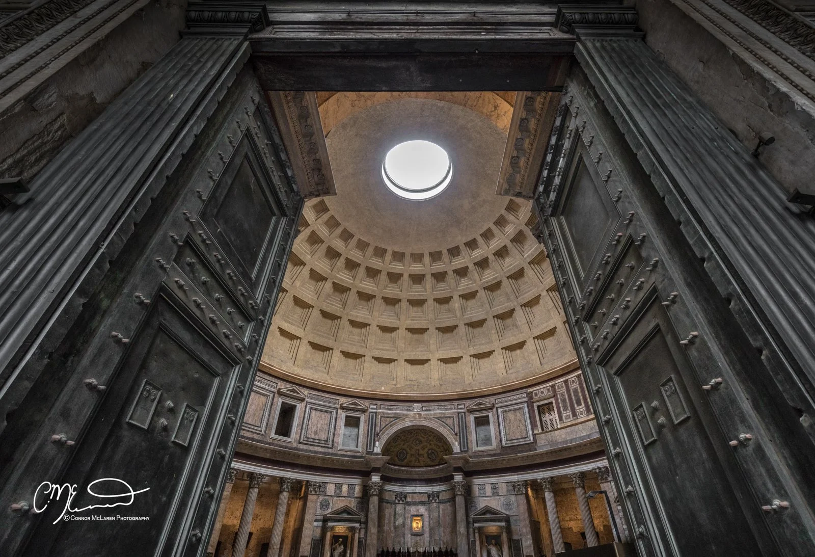 Pantheon, Rome & the vatican. Interior view of a grand, historic building with large, open doors and a circular skylight at the top, showcasing intricate architectural details and columns.