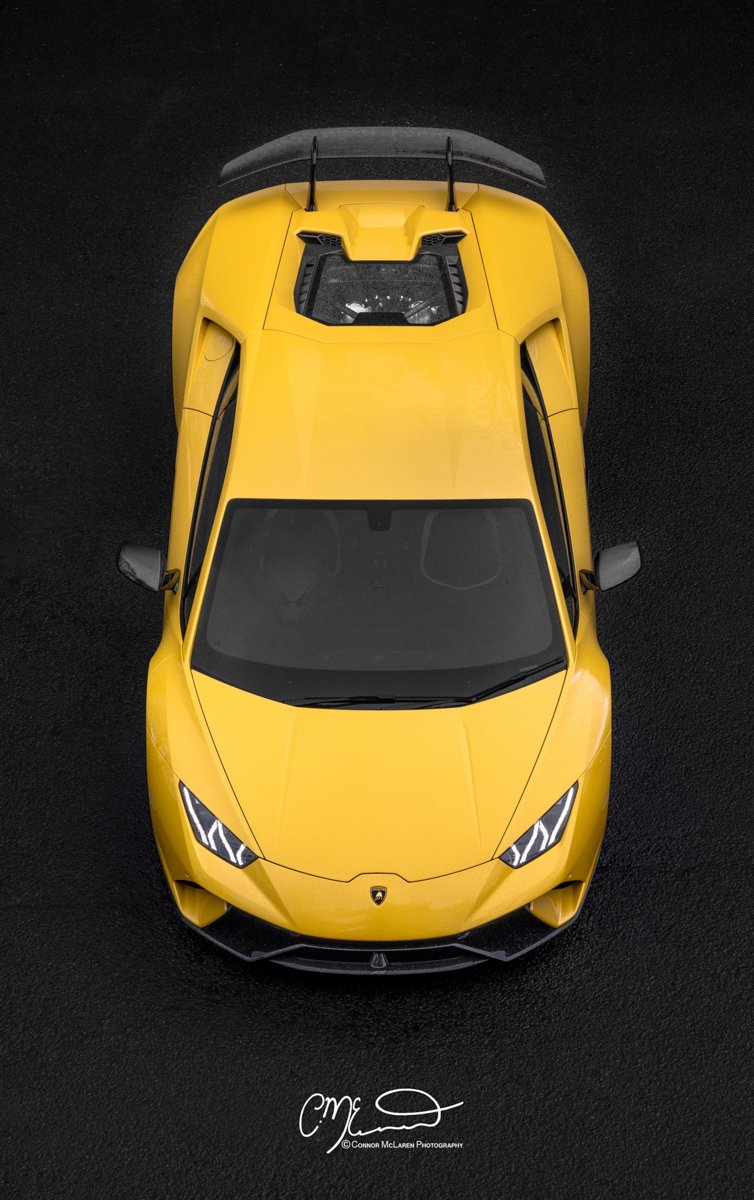 Top view of a bright yellow Lamborghini Performante  sports car on a black asphalt surface.