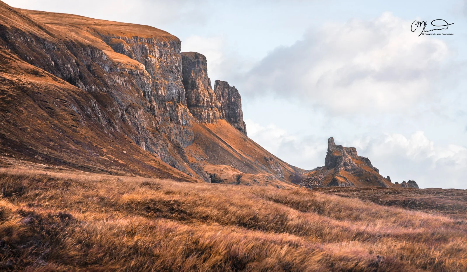 Scotland, Isle of Skye, Quiraing. A rugged mountain landscape with steep, rocky cliffs and grassy slopes under a cloudy sky.