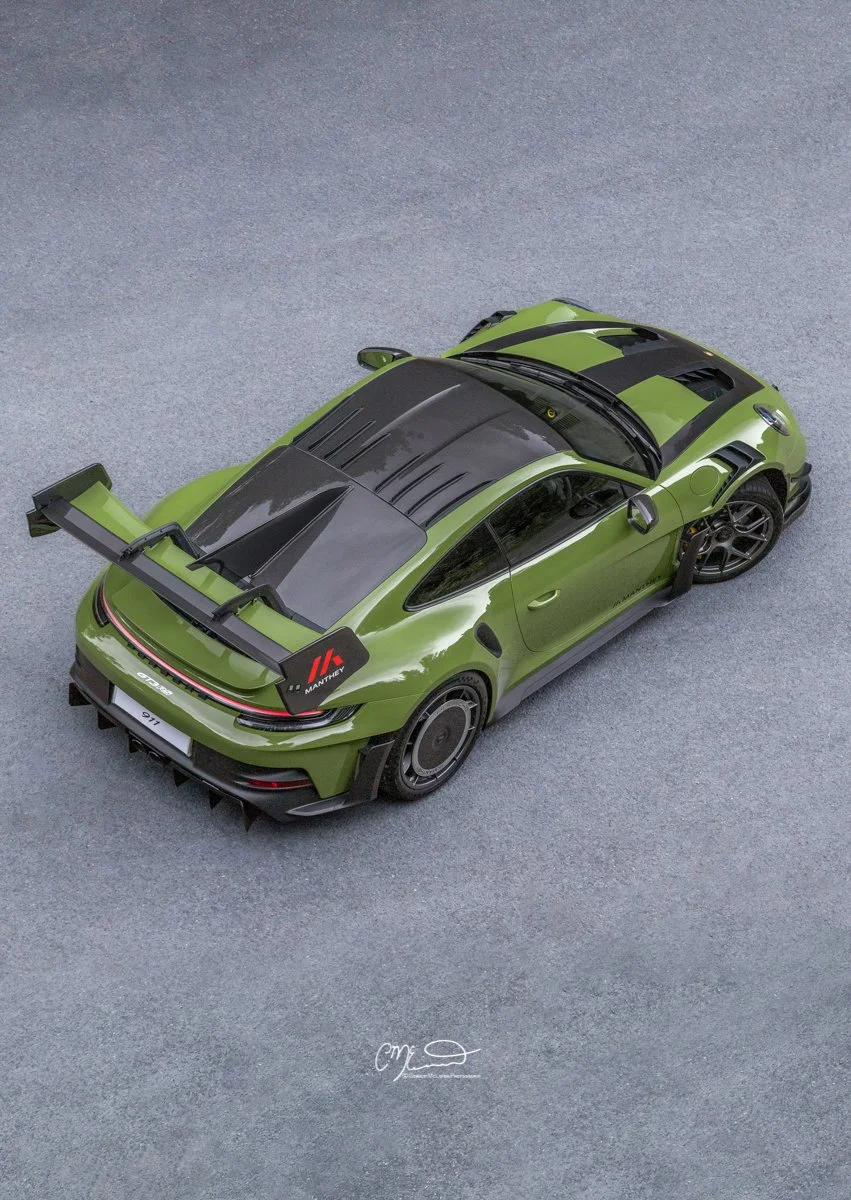 Porsche 911 GT3 RS in Paint to sample Olive green with full Manthey Racing kit. A top-down view of a green race car with a large rear wing, black accents, and black wheels on a gray textured surface.