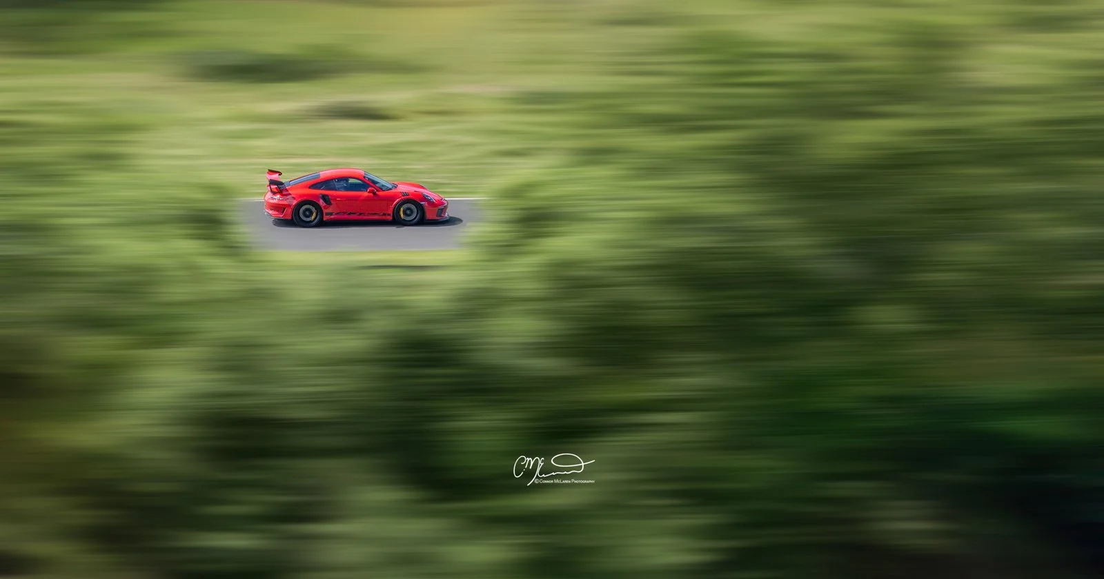 Porsche 911 GT3 RS, 991 racing at knockhill. A red sports car driving on a road with a blurred green background indicating motion.