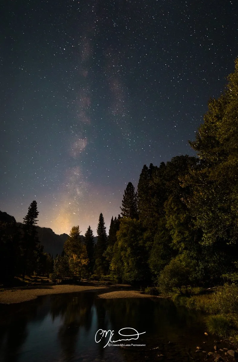 Yosemite national park, usa. Night sky filled with stars over a forested landscape with a river or lake in the foreground.