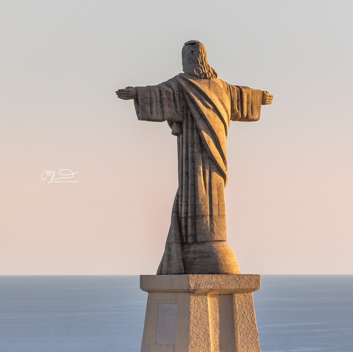 Madeira Portugal. Statue of Jesus Christ with arms open, overlooking the ocean, during sunset.