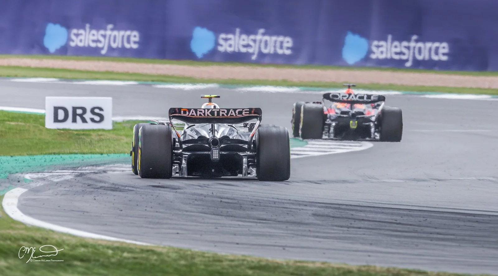 Formula one Silverstone. Two race cars on a track with a background advertising Salesforce, with the car in the foreground labeled DARKTRACE.