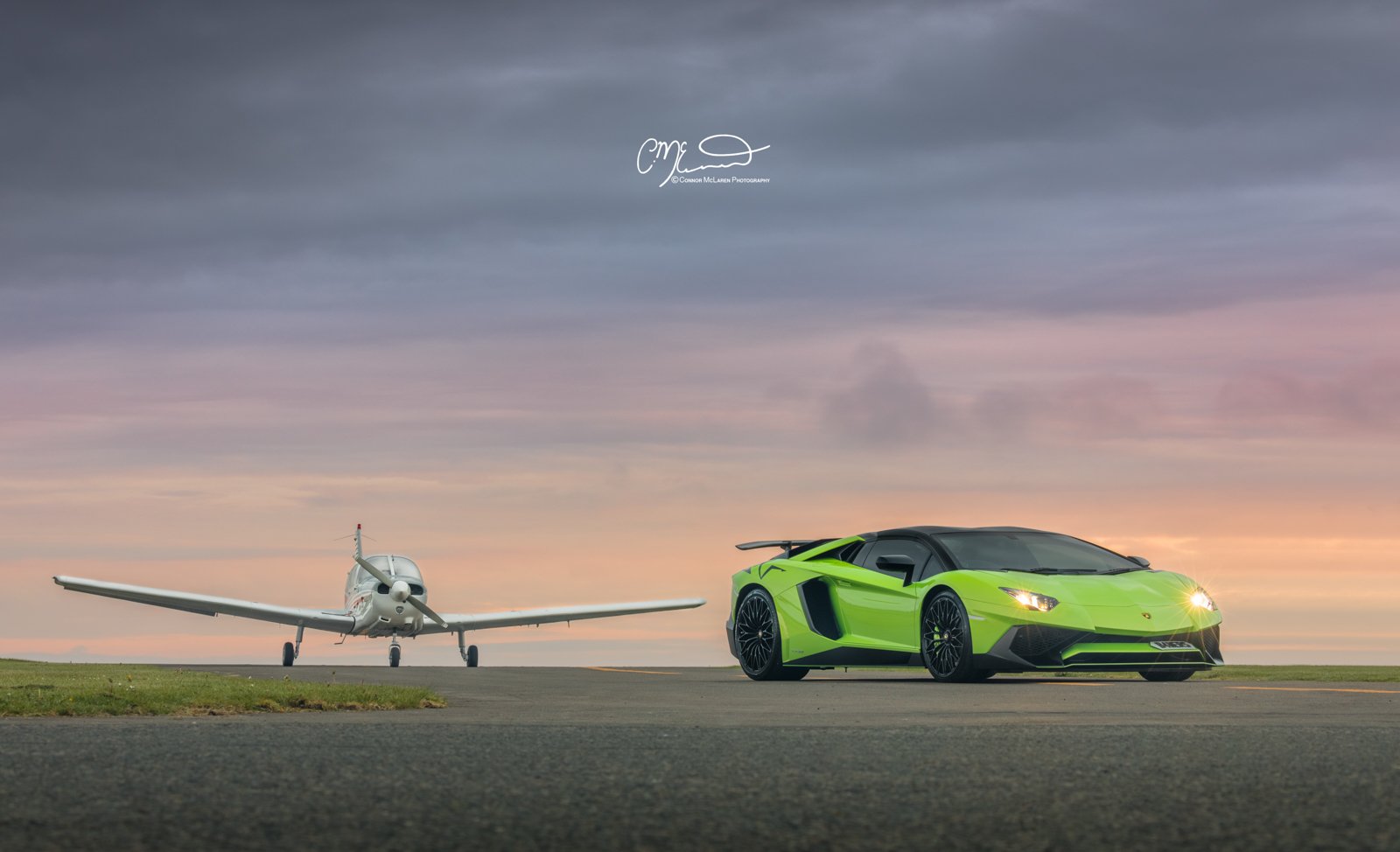 lamborghini Aventador SV Roadster in Green on airport runway with Private jet at sunrise. A green sports car and a white drone aircraft on an empty runway at sunset, viewed from the front.