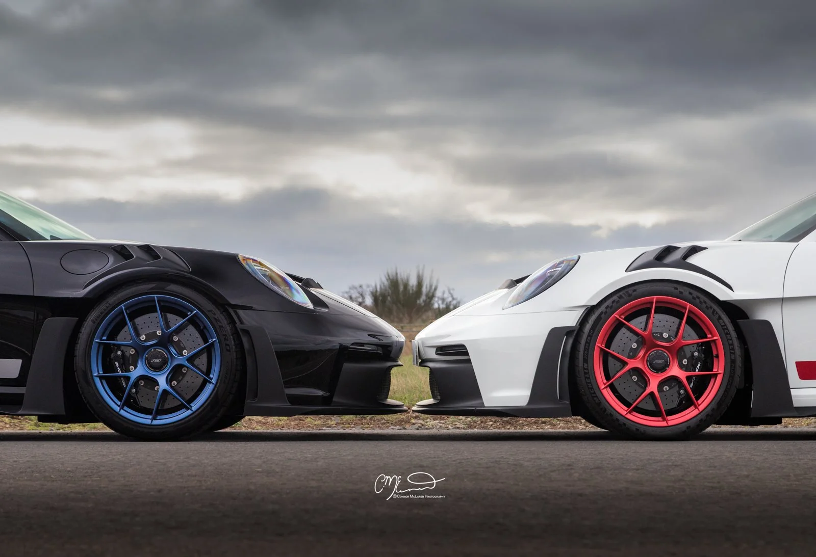 Porsche GT3 RS, A black car and a white car with colorful rims facing each other on a road under a cloudy sky.