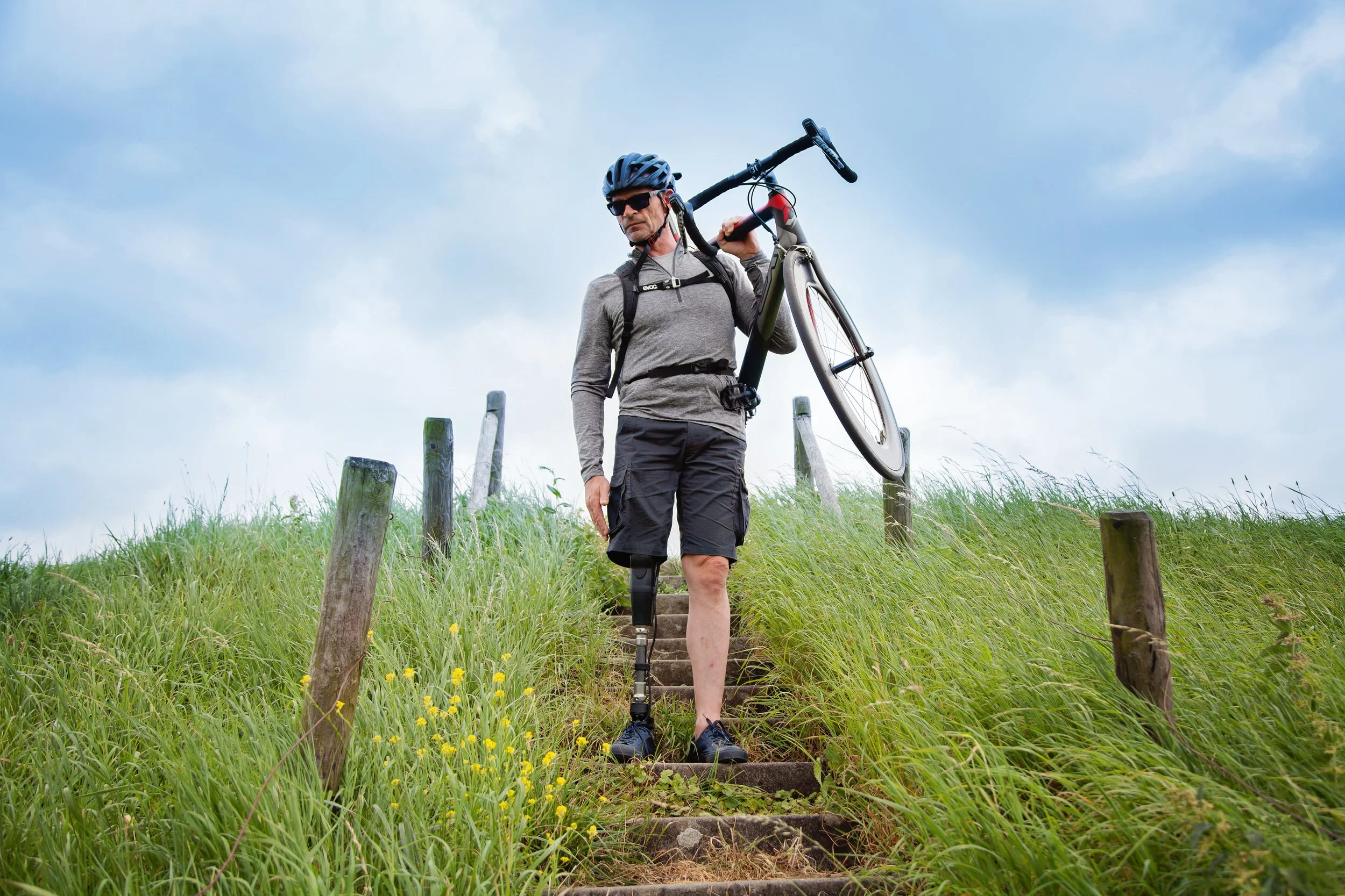 Amputee carrying his bike down stairs on a trail.