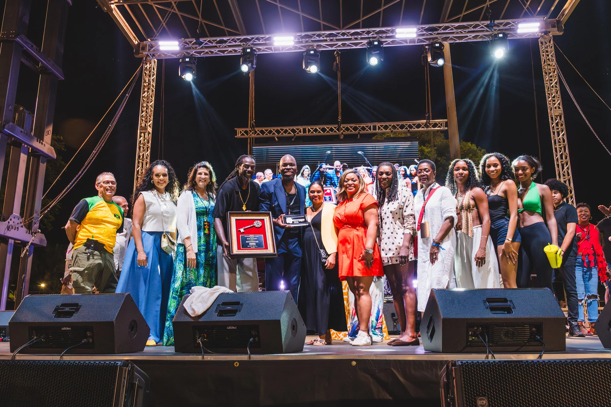 Group of people posing on stage at a live event under concert lighting