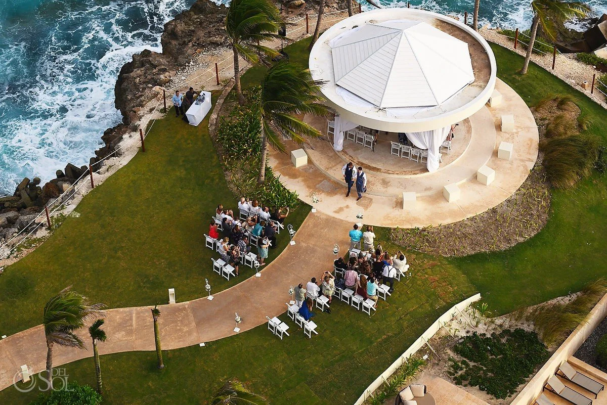 Cliffside garden gazebo wedding venue at Hyatt Ziva Cancun with white pillars, greenery draping, manicured lawn aisle, and turquoise Caribbean ocean backdrop