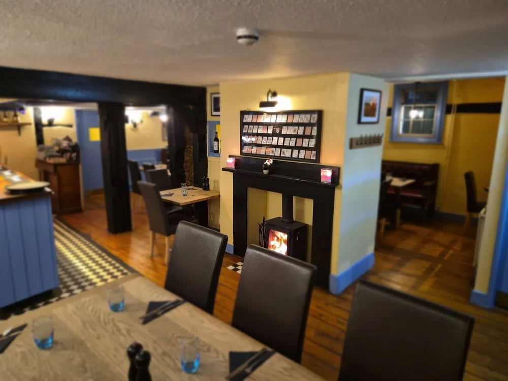 Dining tables beside the lit wood-burning stove at the Kings Arms