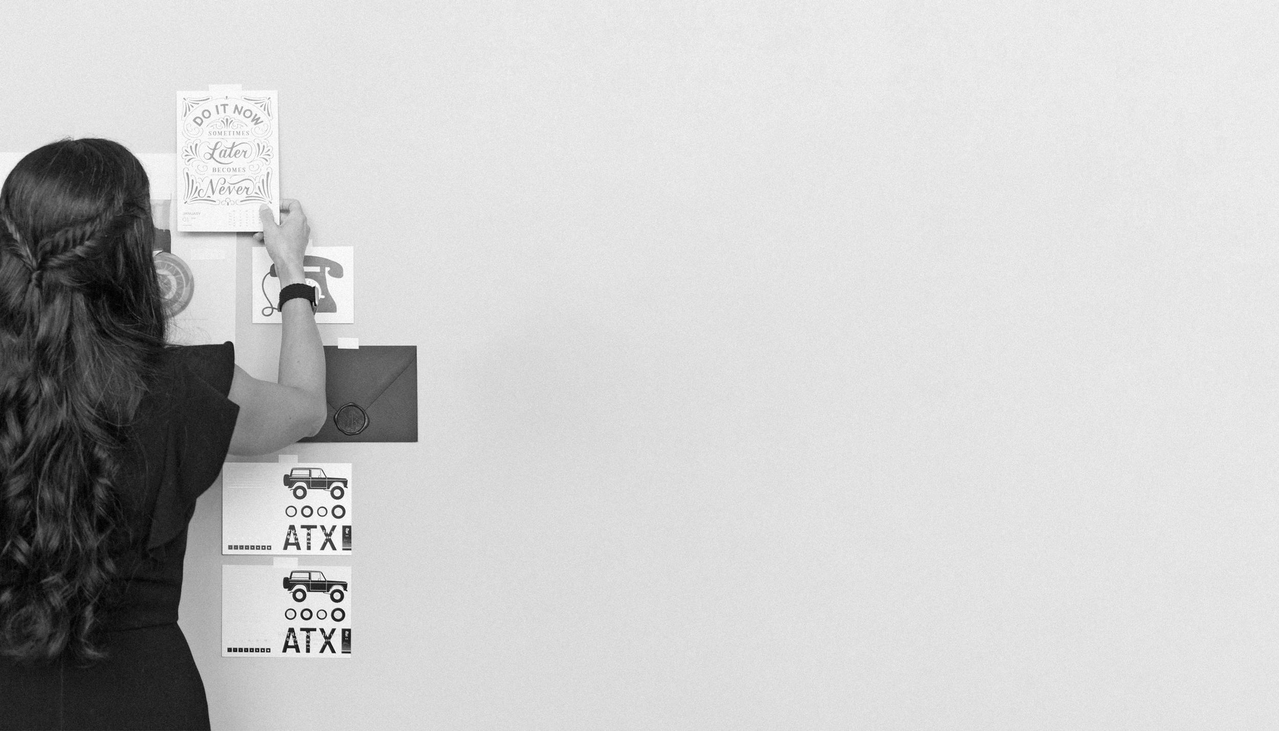 black and white image of a woman pinning brand inspiration images to a mood board for interior designers