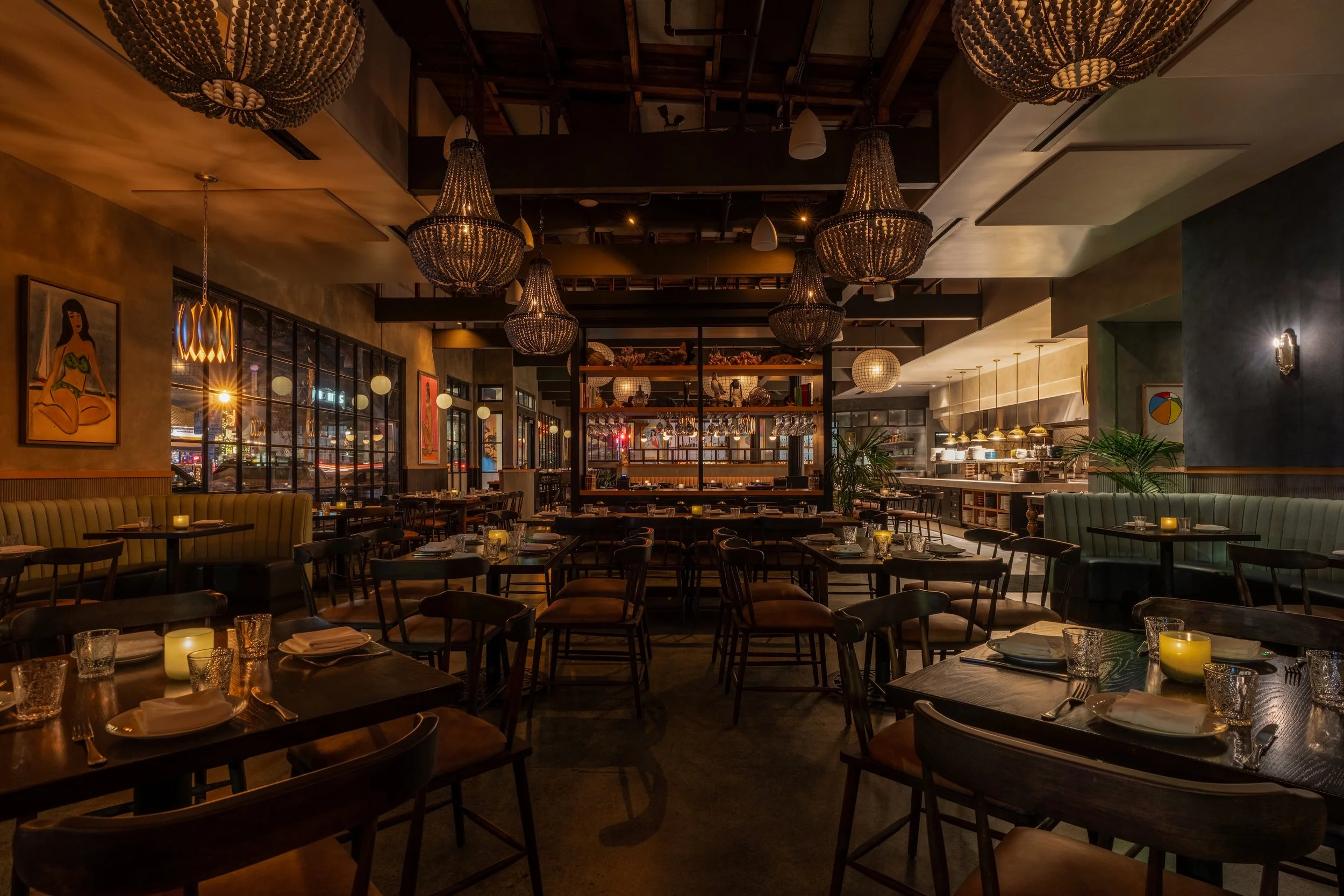 Warm dining room with beaded chandeliers and open kitchen at Herb & Sea private event venue in Encinitas, San Diego
