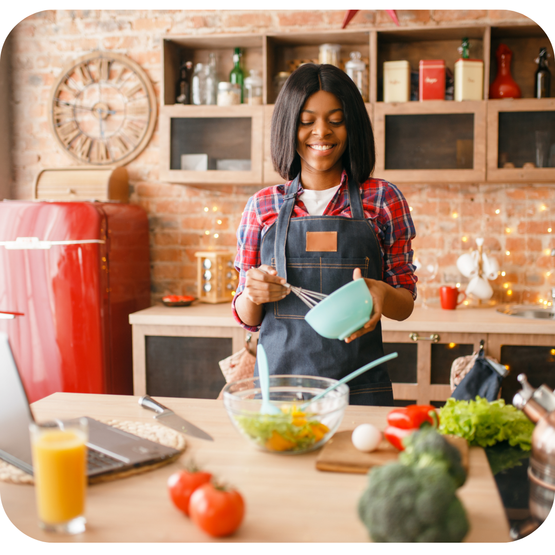 20 something woman whisking in a blue bowl with a laptop on the counter