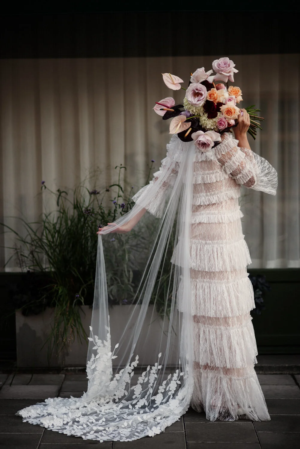 Brud med bröllopsklänning, stor brudbukett och slöja.