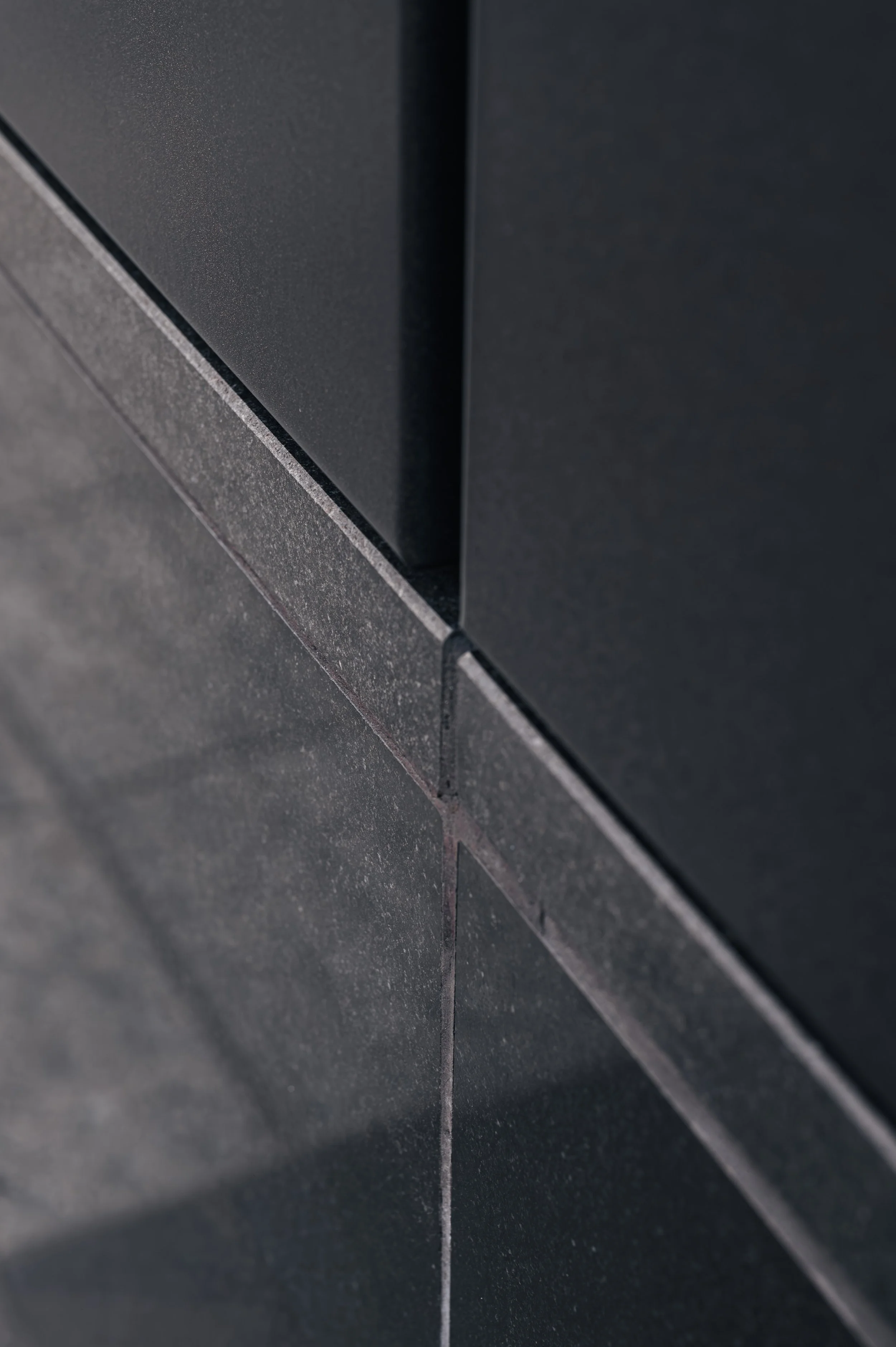 Architectural detail of black stone cladding at JP Morgan building in Glasgow showing surface texture.