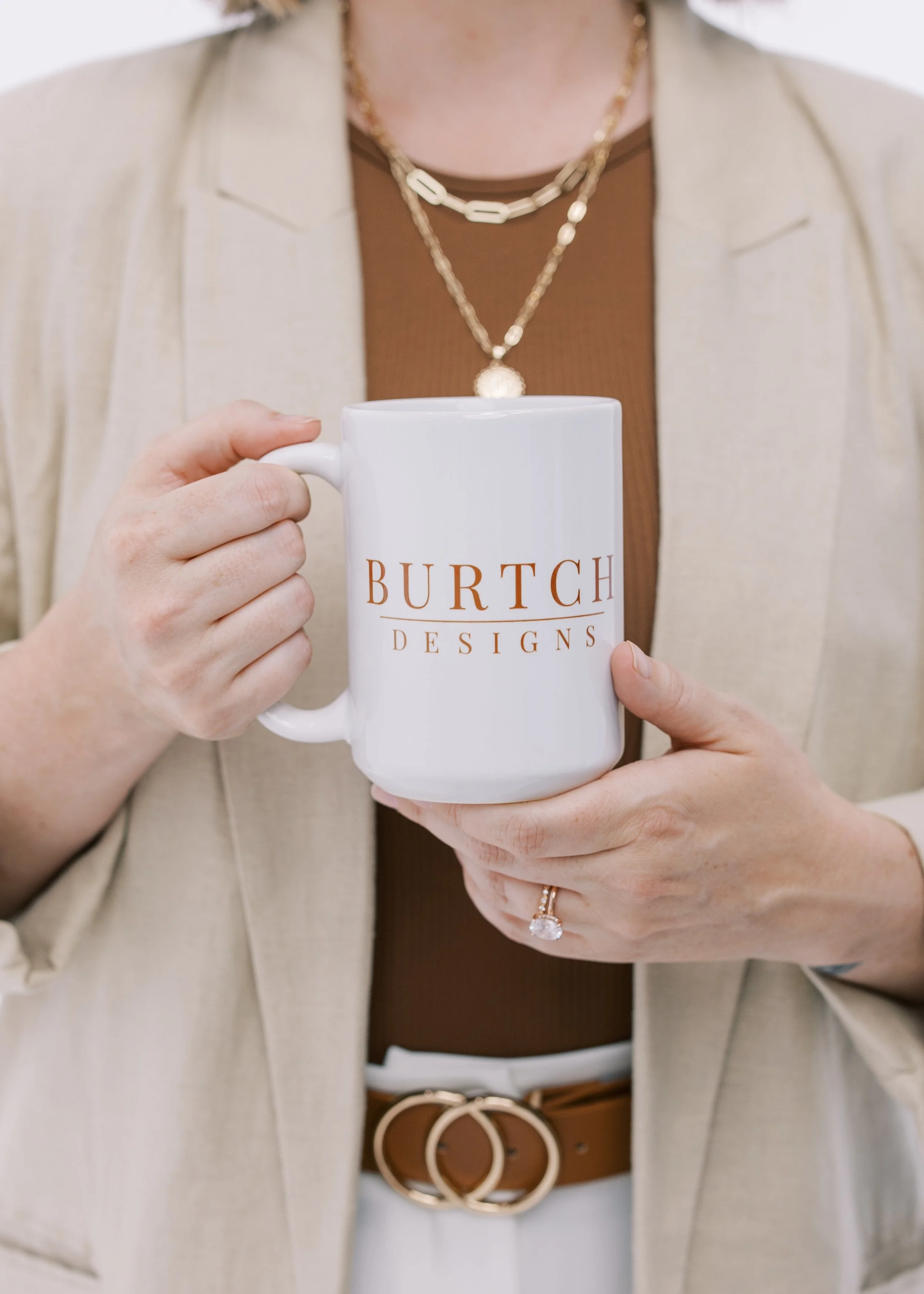 Jackie holding a white mug with "BURTCH DESIGNS" printed on it.