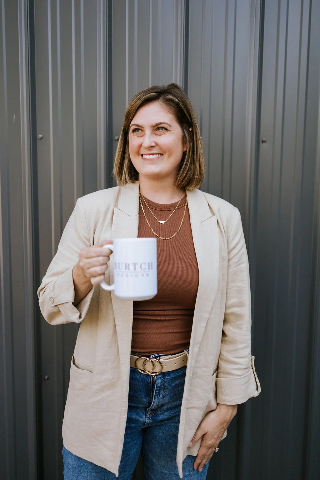 Jackie smiling and holding a branded white mug