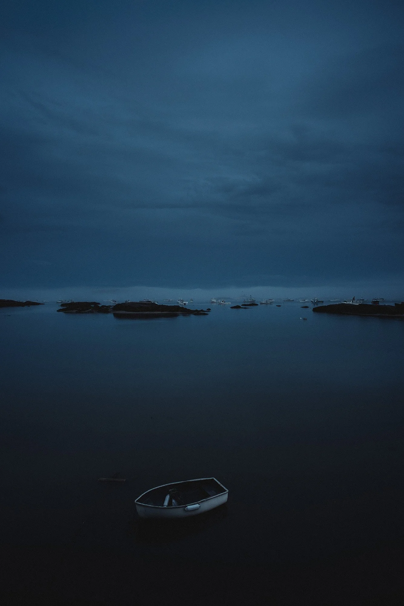 Moody blue-hour landscape photography of a lone boat by Scorpion Rose Studio and Lafayette American. Cinematic atmospheric lighting and visual storytelling for an agency portfolio.