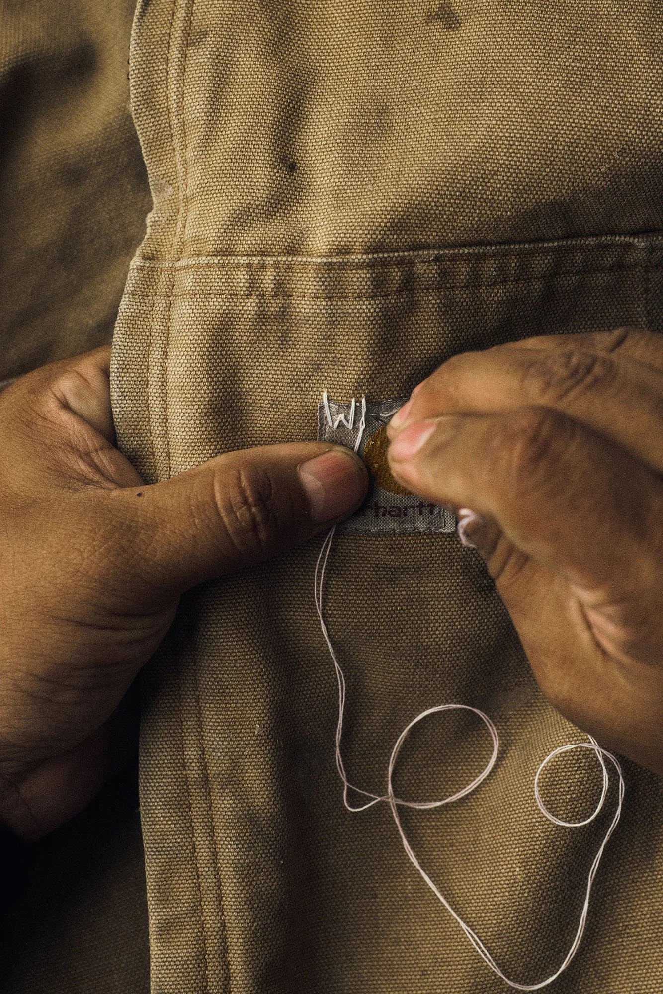 Behind-the-scenes detail for Scorpion Rose Studio and Lafayette American: Hands carefully embroidering thread through workwear canvas, highlighting authentic, handcrafted design processes.