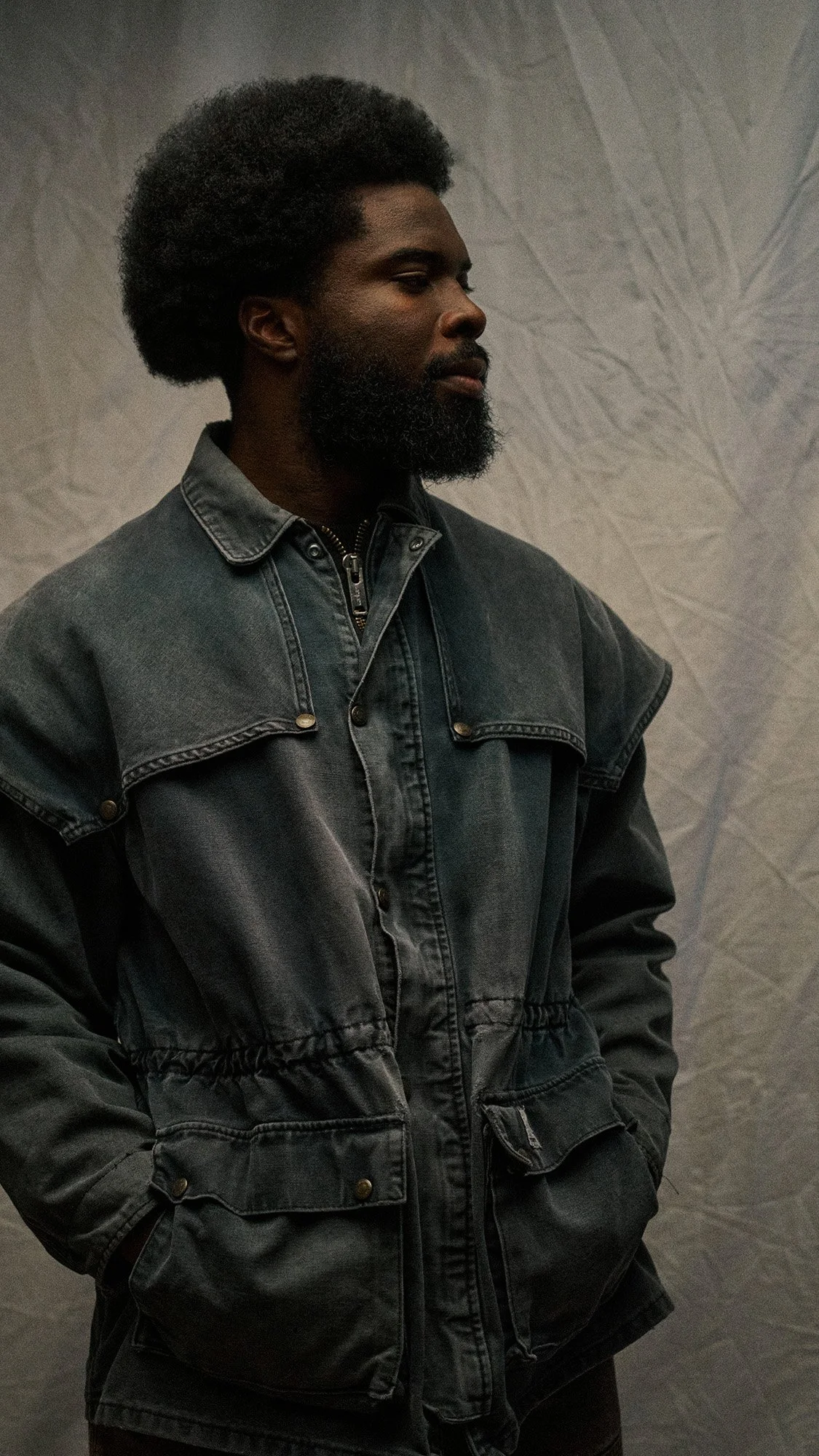 Studio portrait for Wylie Welling by Scorpion Rose Studio & Lafayette American: Model in a weathered, multi-pocket charcoal work jacket against a textured backdrop for brand editorial.