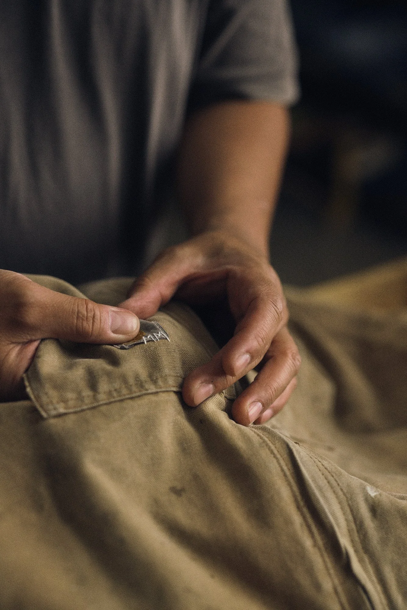 Craftsmanship photography for Scorpion Rose Studio & Lafayette American: Detailed shot of hands finishing a custom garment tag, emphasizing quality and artisanal brand identity.