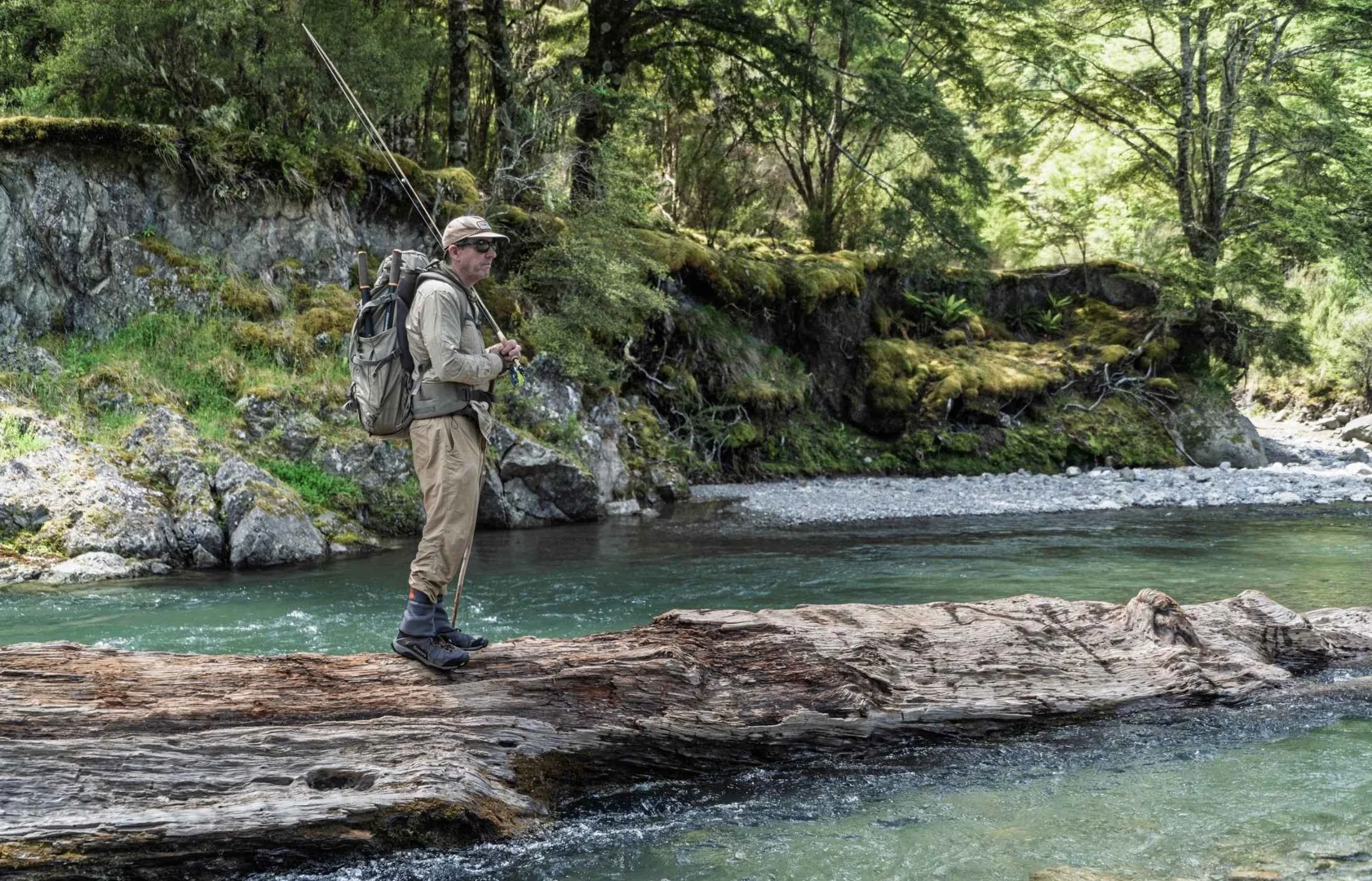 Fly fisherman casting into a remote New Zealand river accessed by helicopter